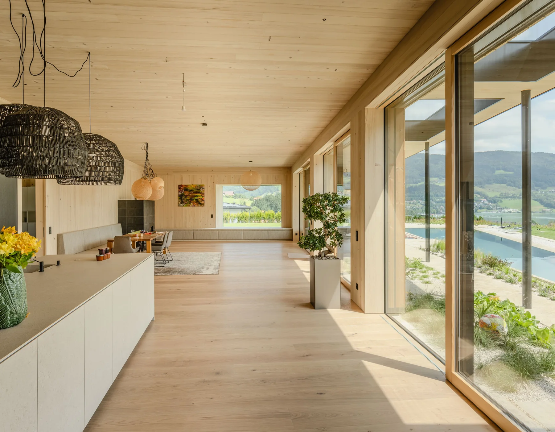 Lichtdurchfluteter Wohnraum mit ACTUAL Holz-Alu-Fenstern und großflächigen Schiebeelementen.